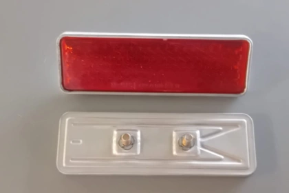 03035 - Catadiottro rosso con bordo in metallo, mm 132 × 43, distanza viti mm 40